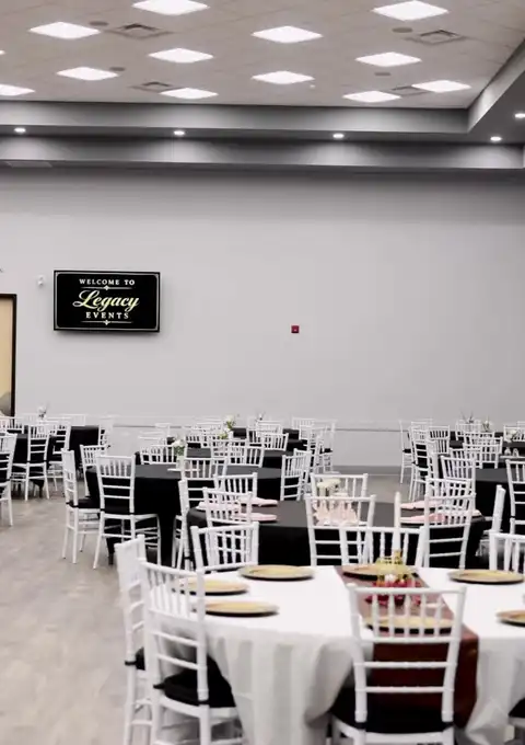 Ballroom set with round tables, white chairs, and a welcome sign