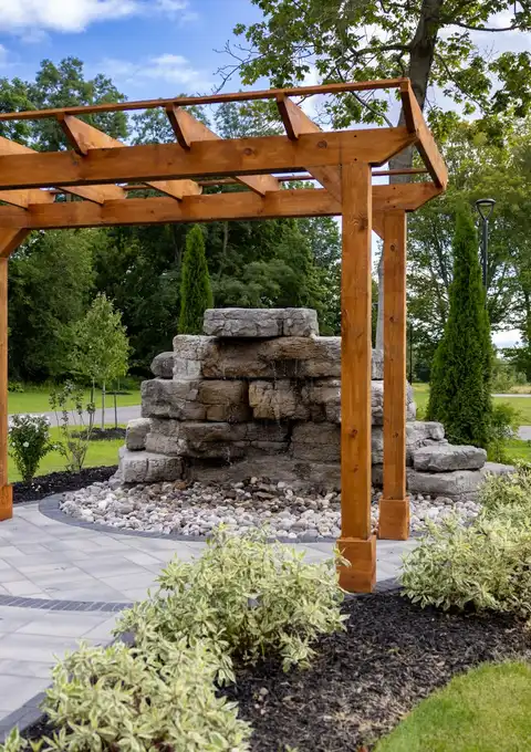 Timber pergola beside a stone waterfall in the landscaped garden