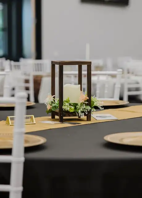 Table with a lantern centrepiece and gold chargers at Legacy Events