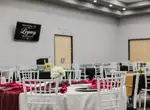 Ballroom tables set with red linens beneath a Legacy Events welcome screen